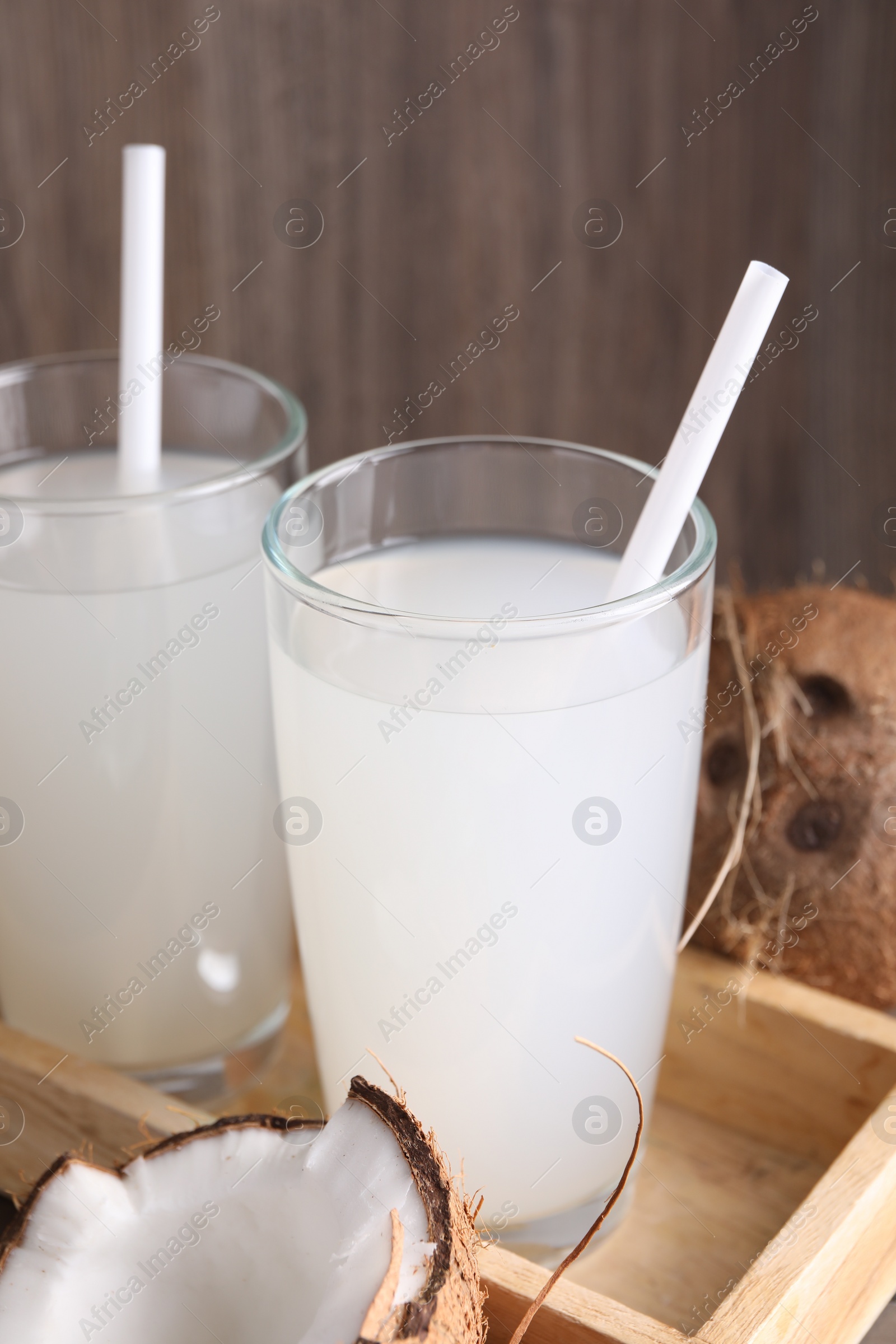 Photo of Glasses of coconut water with straws and nuts on table