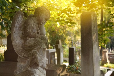 Beautiful statue of angel at cemetery on sunny day, space for text. Funeral ceremony