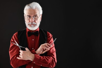 Senior man with mustache holding blade and scissors on black background, space for text