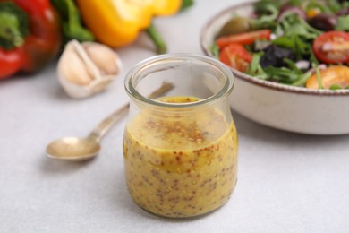 Photo of Tasty vinegar based sauce (Vinaigrette) in jar on light table, closeup