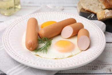 Photo of Delicious boiled sausages, fried eggs and dill on wooden table, closeup