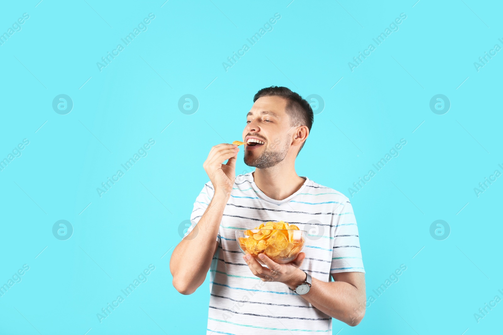 Photo of Man eating potato chips on color background