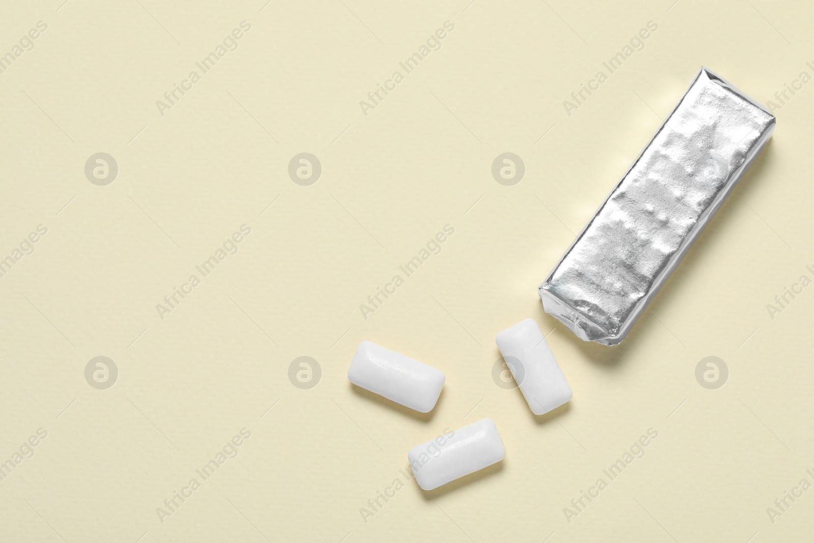 Photo of Pack with tasty chewing gums on beige background, flat lay. Space for text