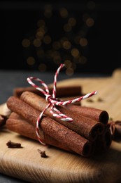 Photo of Cinnamon sticks and other spices on table against black background with blurred lights, closeup