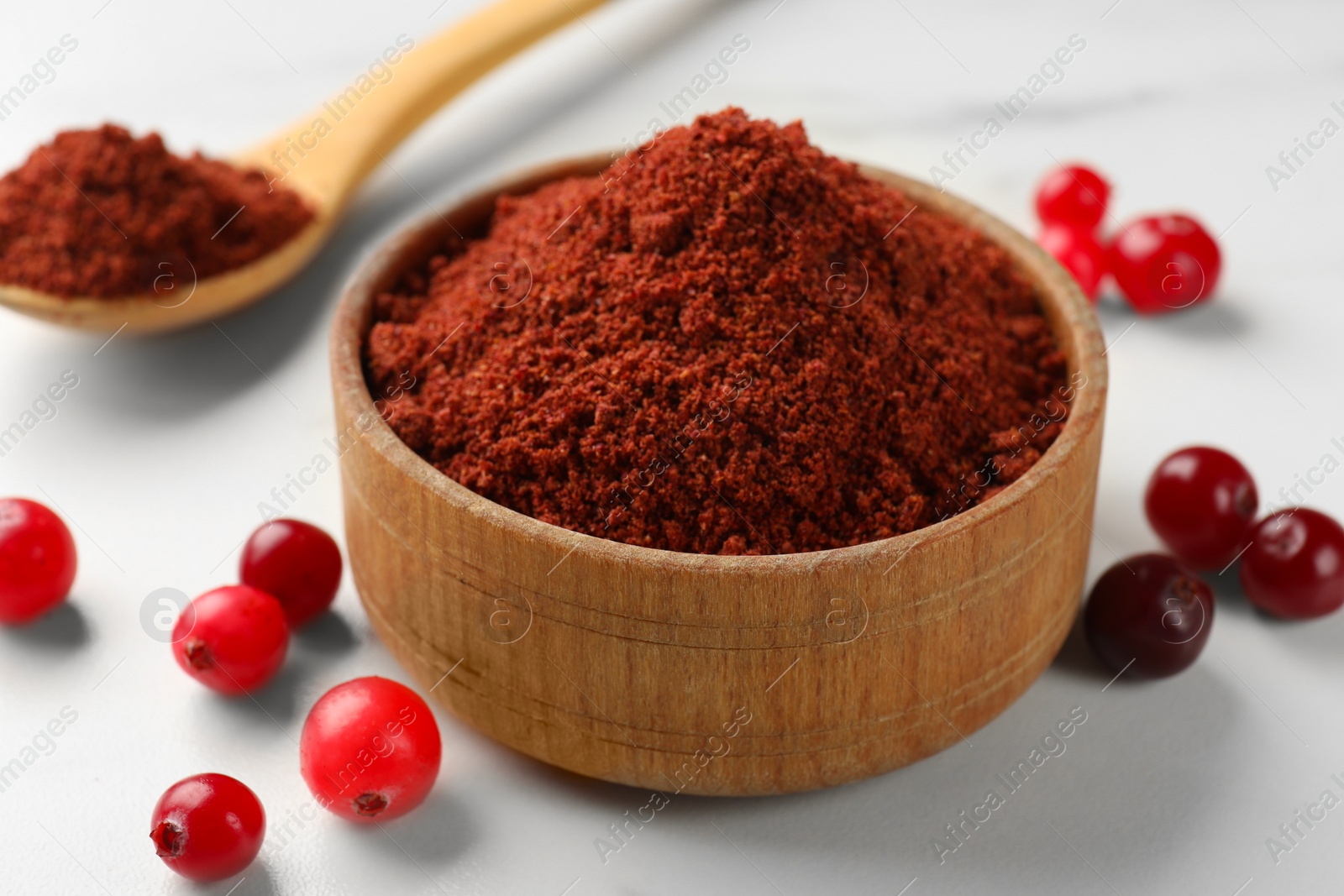 Photo of Dried cranberry powder and fresh berries on white table, closeup