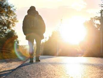 Photo of Man walking along road on sunny day, back view. Space for text