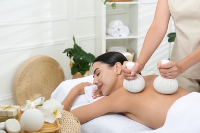 Photo of Young woman receiving herbal bag massage in spa salon