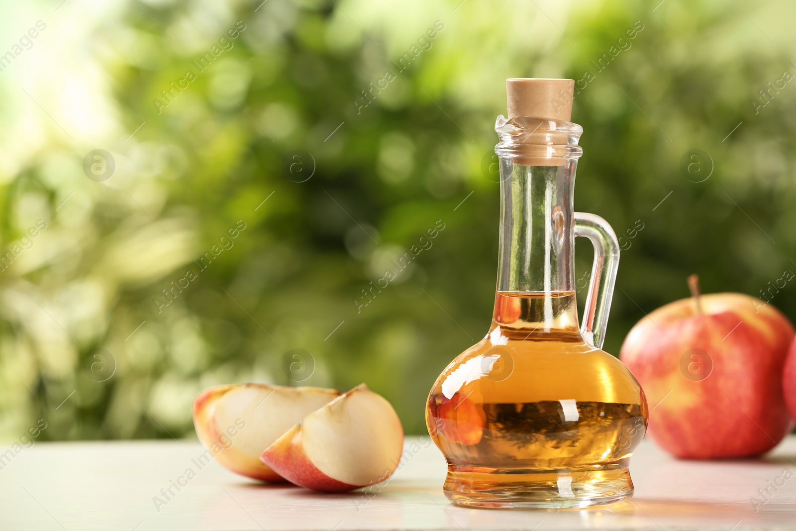 Photo of Composition with jug of apple vinegar on table. Space for text