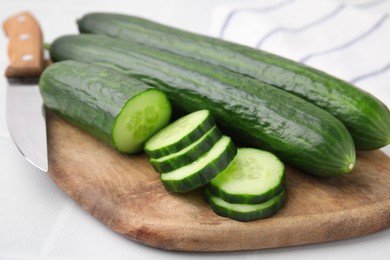 Photo of Fresh whole and cut cucumbers on white table, closeup