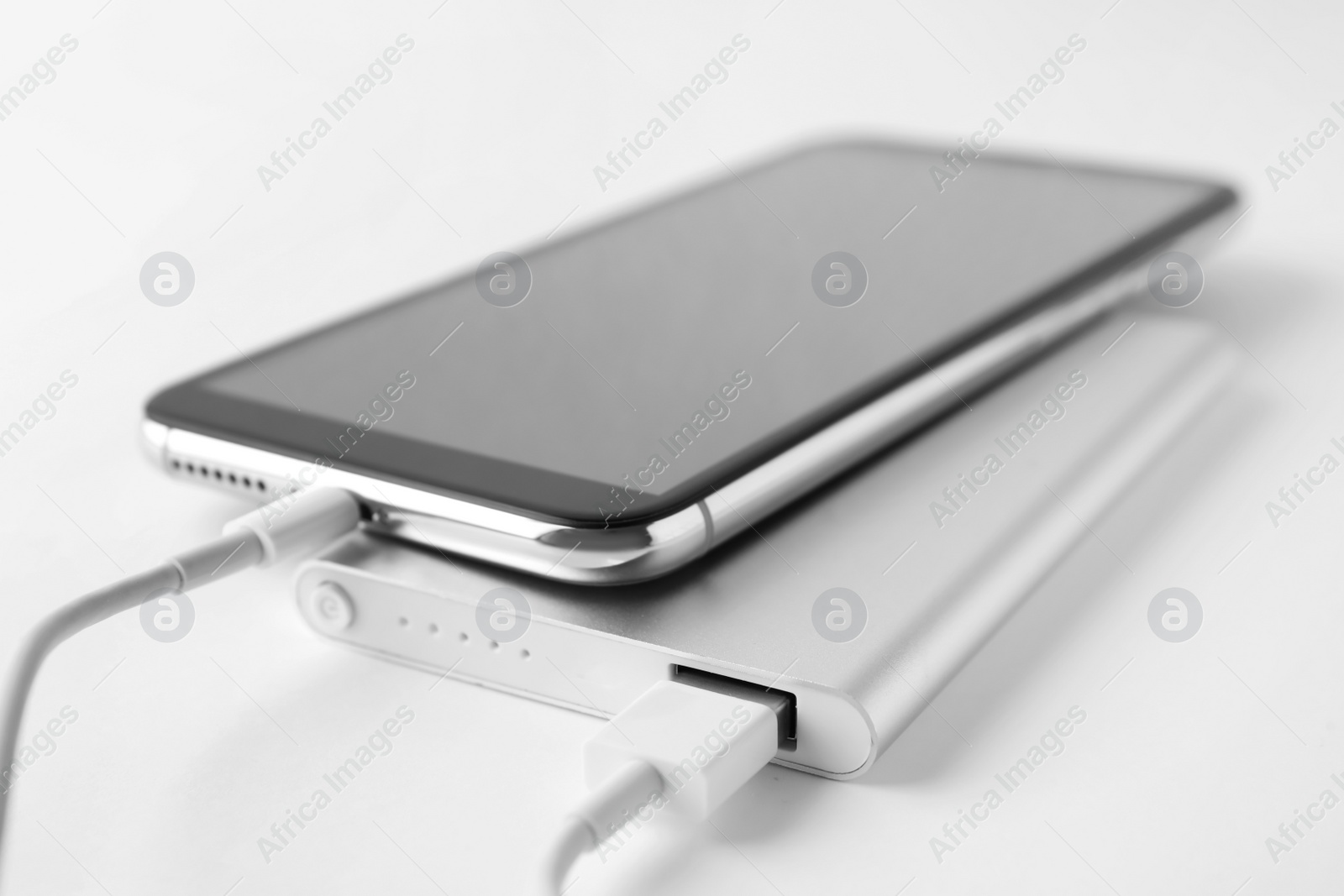 Photo of Smartphone charging with power bank on white background, closeup