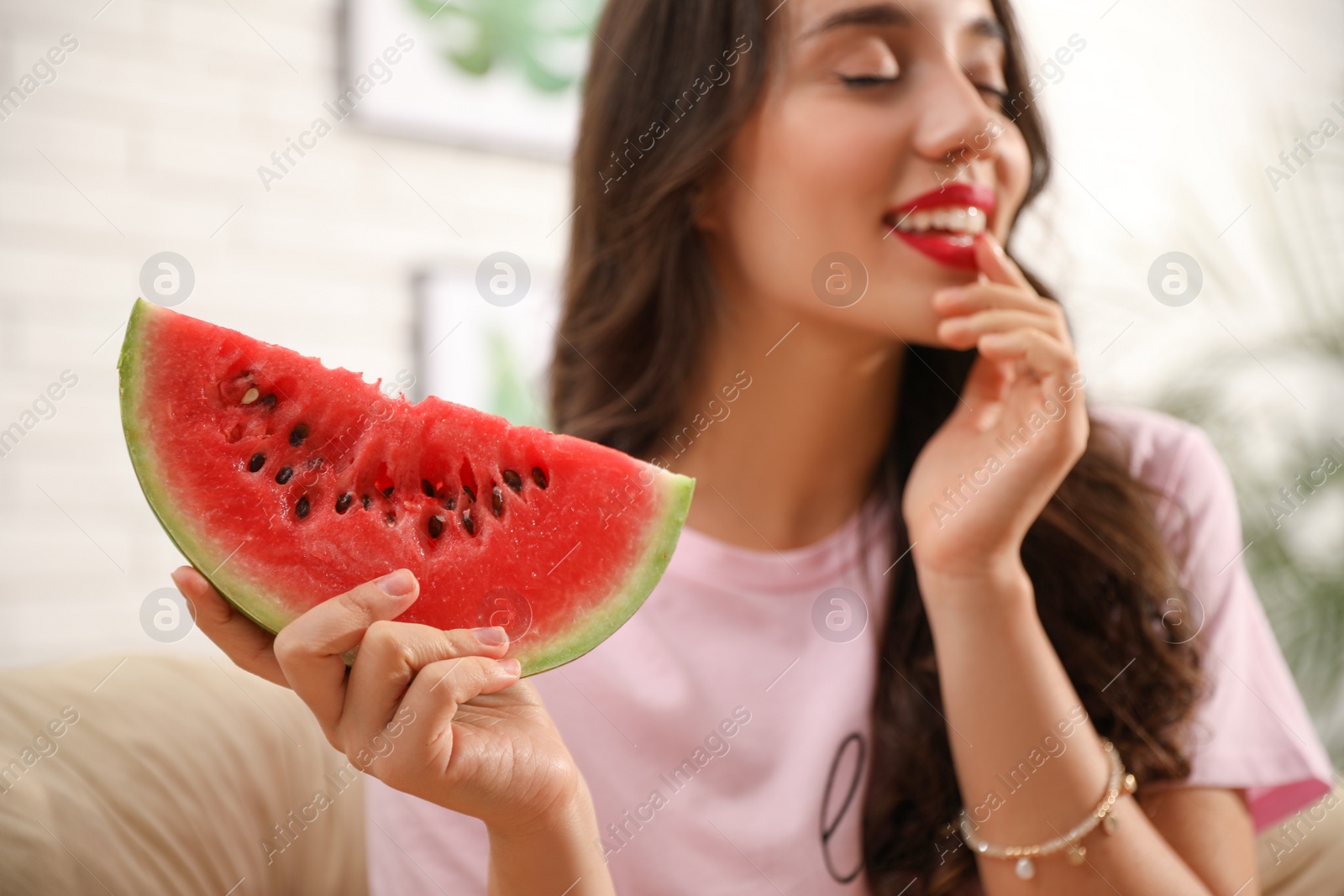 Photo of Beautiful young woman at home, focus on hand with watermelon