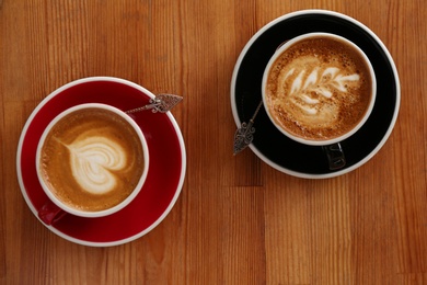 Cups of fresh aromatic coffee on wooden table, top view