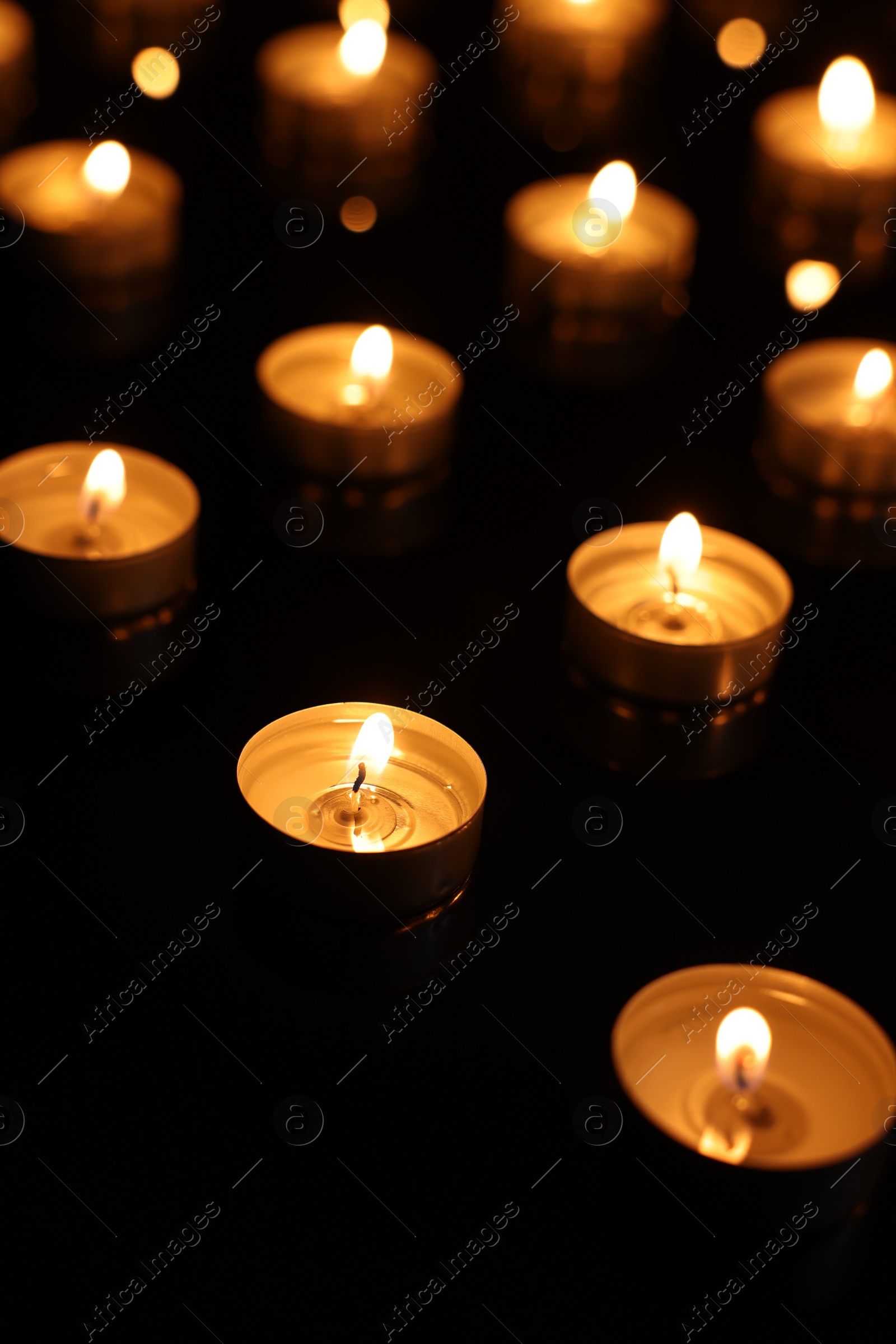 Photo of Burning candles on mirror surface in darkness