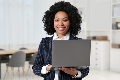 Photo of Smiling young businesswoman using laptop in office