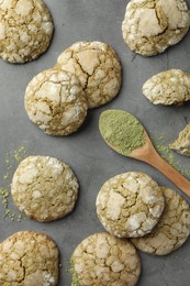Photo of Tasty matcha cookies and wooden spoon of powder on grey table, flat lay