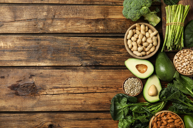 Different products rich in vitamin E on wooden table, flat lay. Space for text