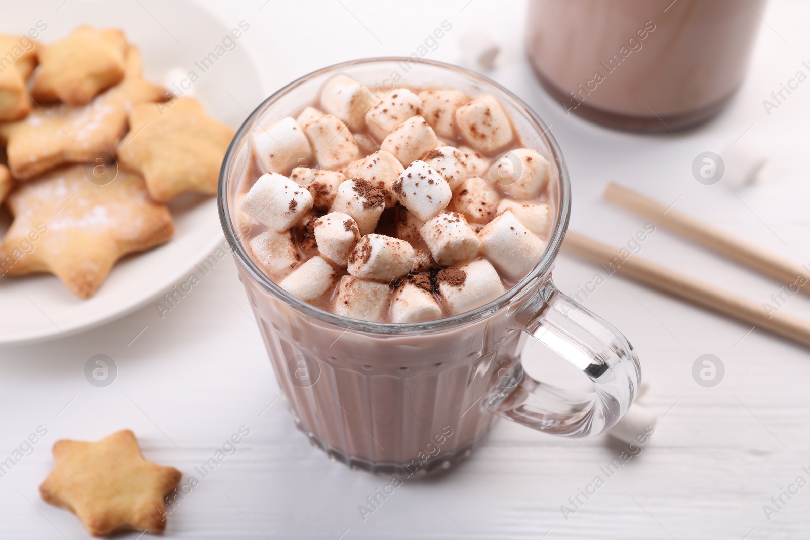 Photo of Cup of aromatic hot chocolate with marshmallows, cocoa powder and tasty cookies on white table, closeup