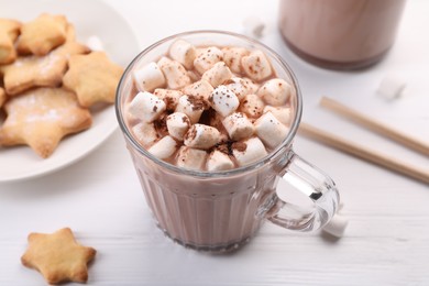 Cup of aromatic hot chocolate with marshmallows, cocoa powder and tasty cookies on white table, closeup
