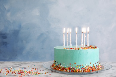 Fresh delicious birthday cake with candles on table against color background. Space for text