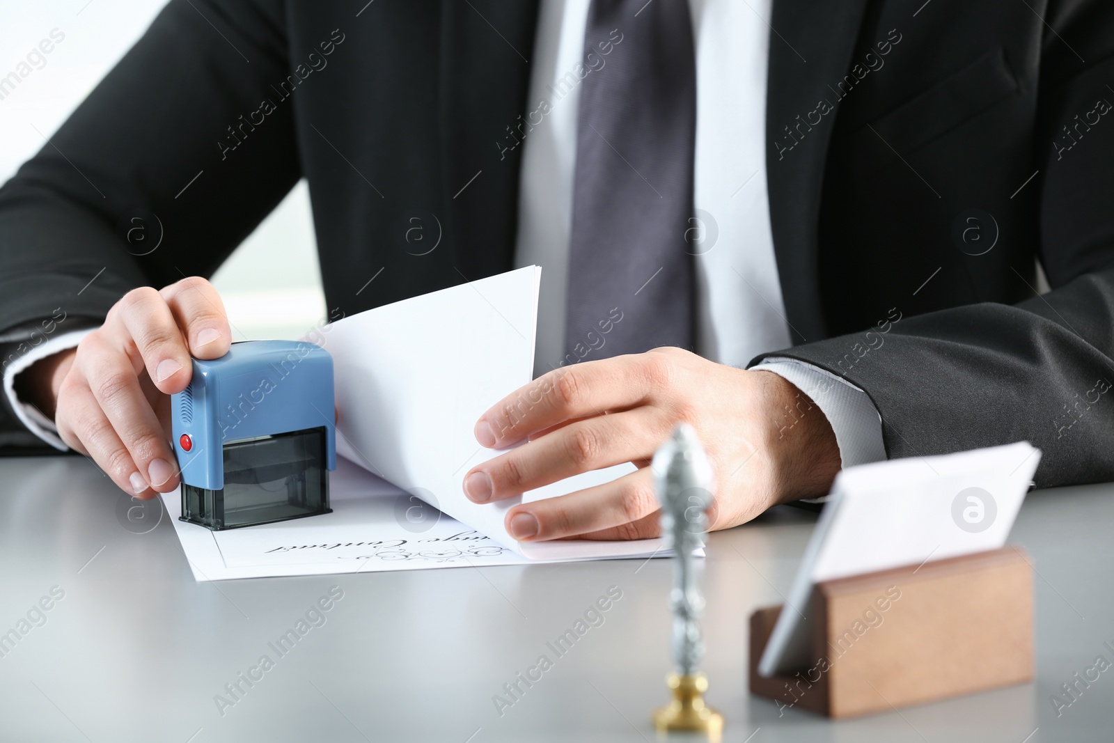Photo of Male notary stamping document at table, closeup