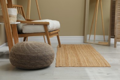 Photo of Stylish knitted pouf and armchair in room