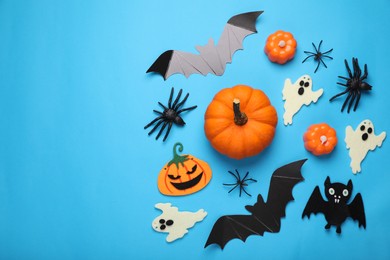 Flat lay composition with bats, pumpkins, ghosts and spiders on light blue background, space for text. Halloween celebration