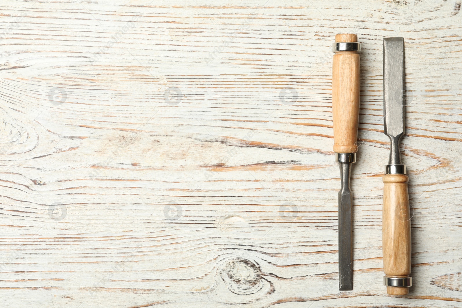 Photo of Chisels on white wooden background, flat lay with space for text. Carpenter's tools