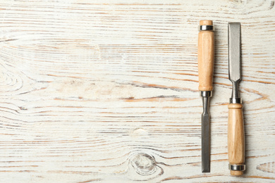 Photo of Chisels on white wooden background, flat lay with space for text. Carpenter's tools