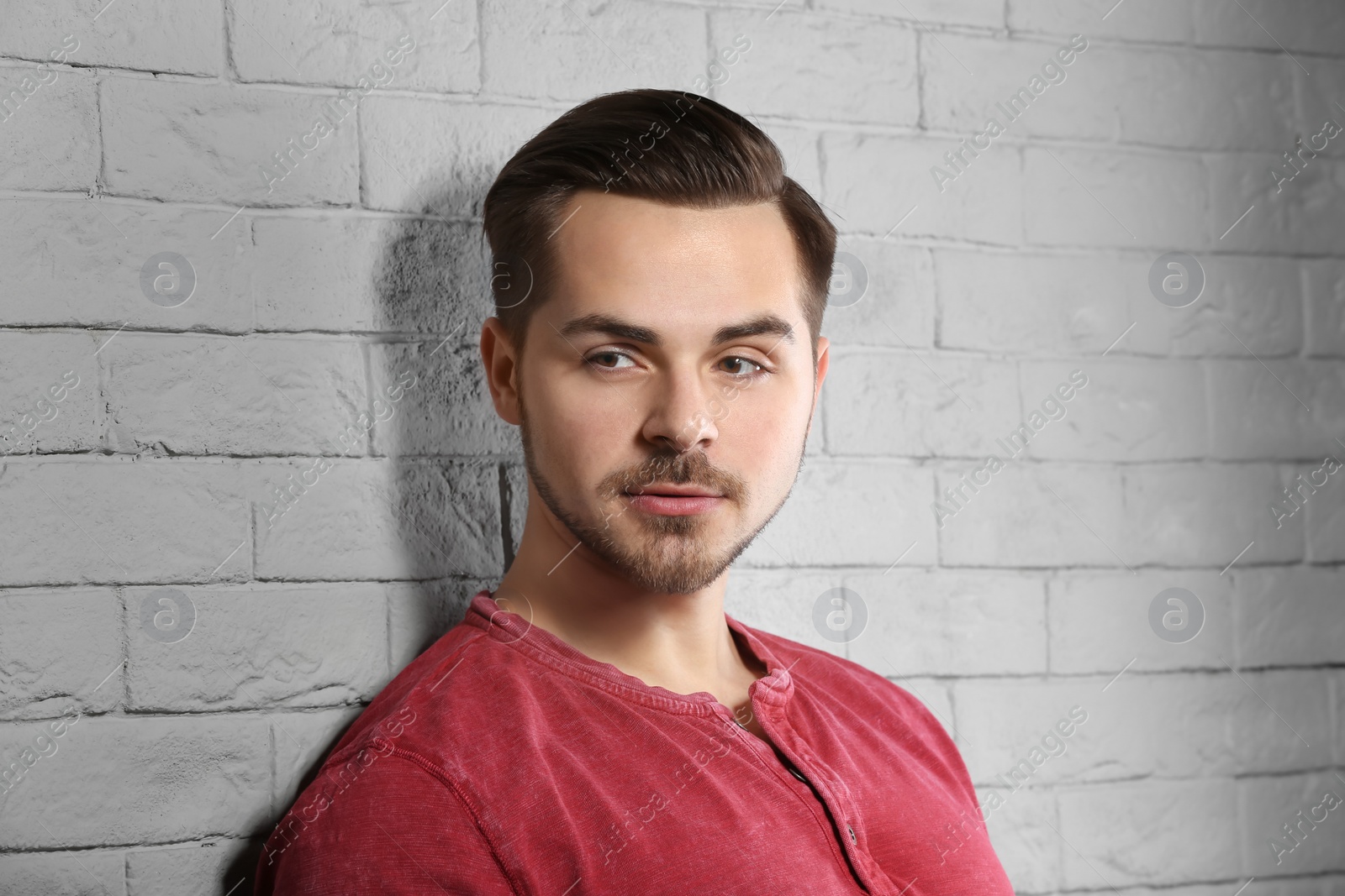 Photo of Portrait of young man with beautiful hair on brick wall background