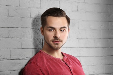 Portrait of young man with beautiful hair on brick wall background