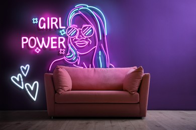 Image of Glowing neon sign with outline of woman, hearts and words Girl Power near couch on wall indoors
