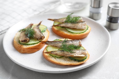 Photo of Delicious sandwiches with sprats, cucumbers and dill on light table