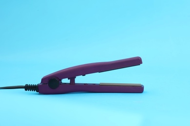 Photo of Modern hair iron for straightening on color background. Space for text