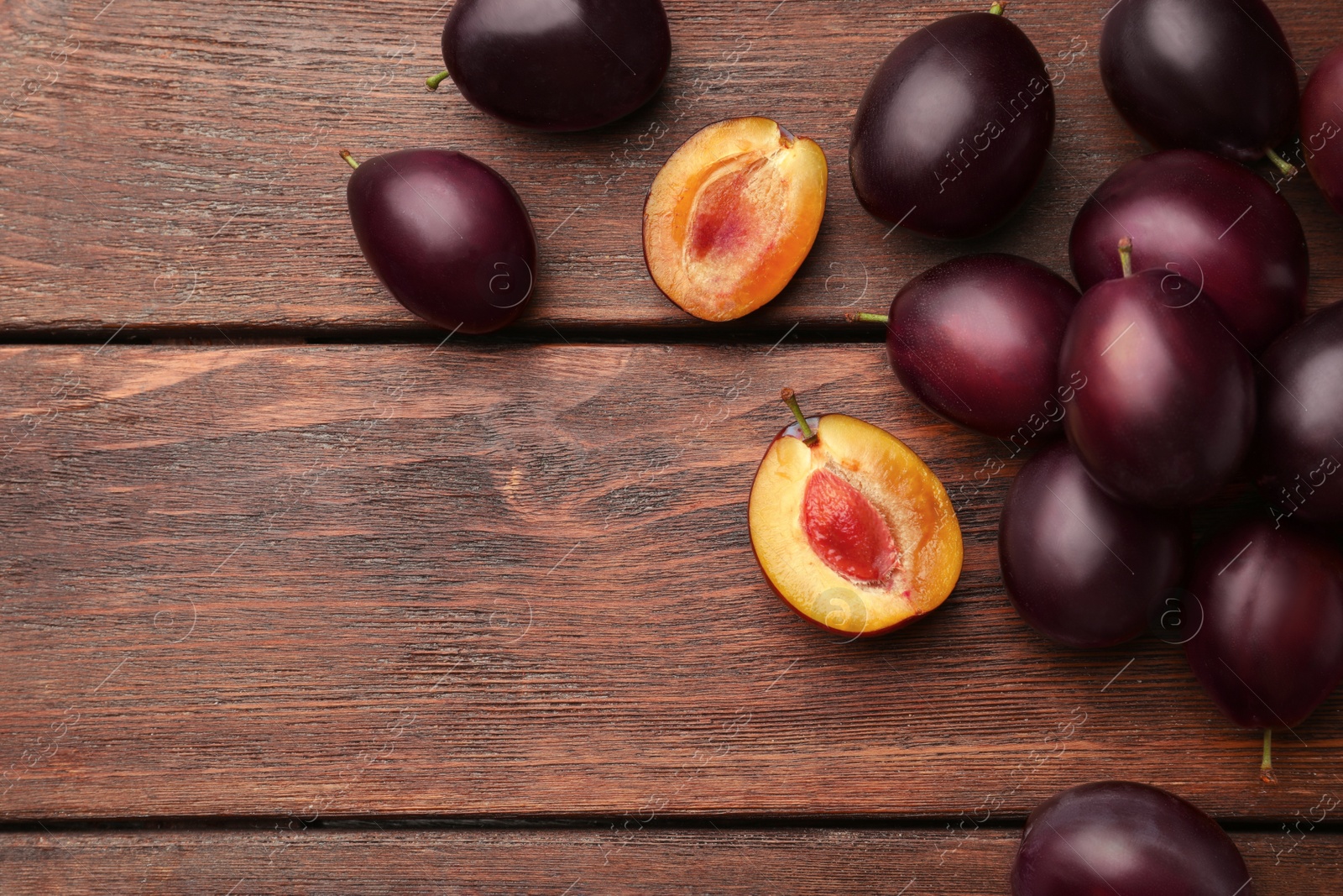 Photo of Tasty ripe plums on wooden table, flat lay. Space for text