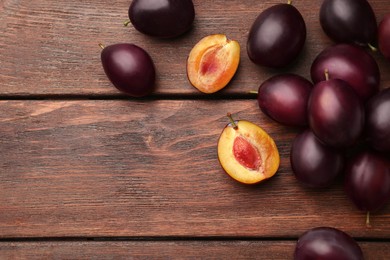 Tasty ripe plums on wooden table, flat lay. Space for text