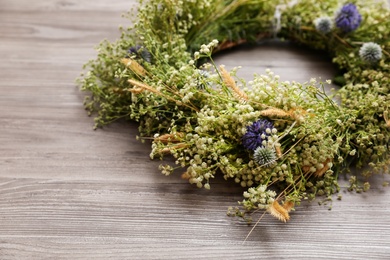 Beautiful wreath made of wildflowers on wooden background, closeup