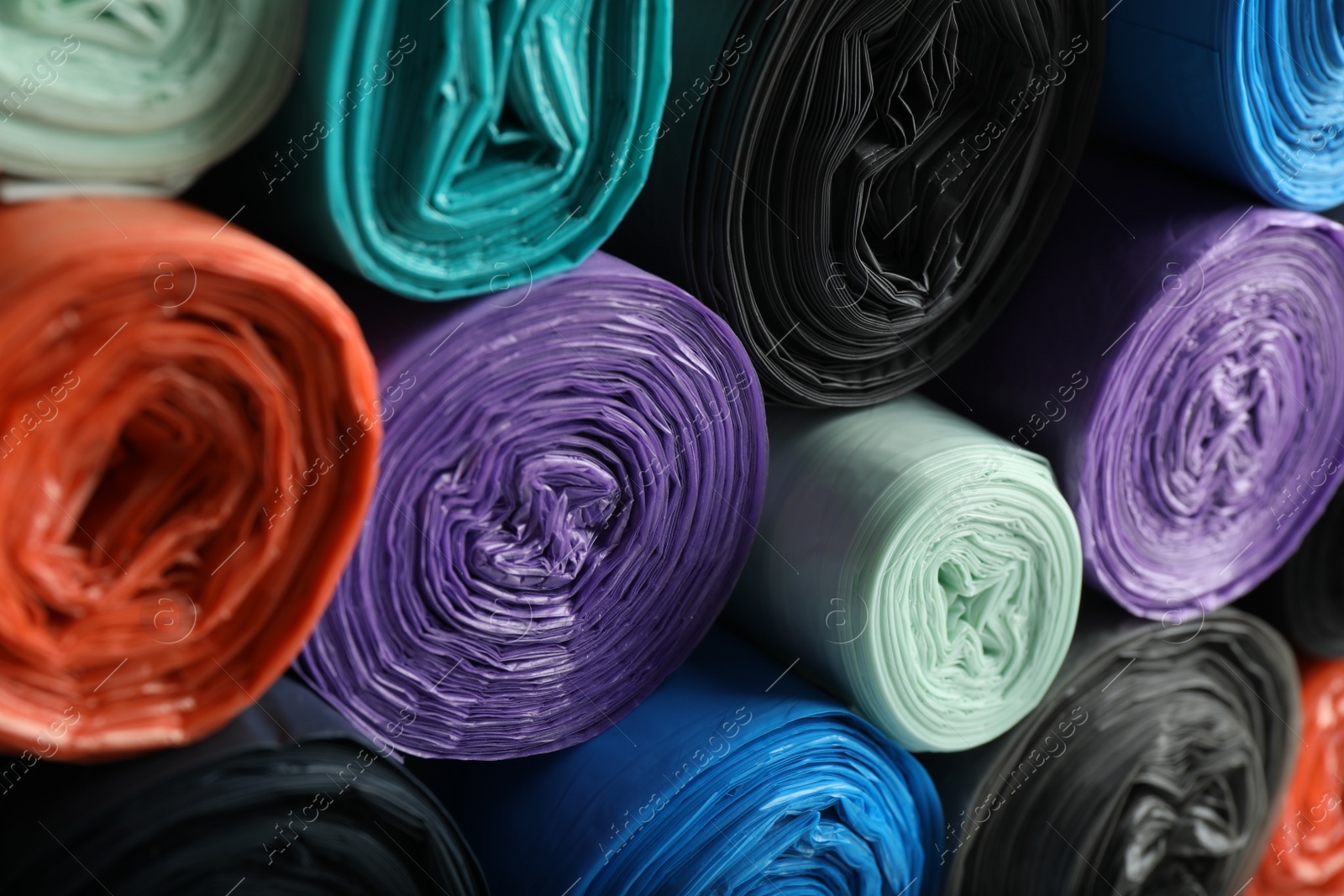 Photo of Rolls of different color garbage bags as background, closeup