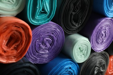 Photo of Rolls of different color garbage bags as background, closeup