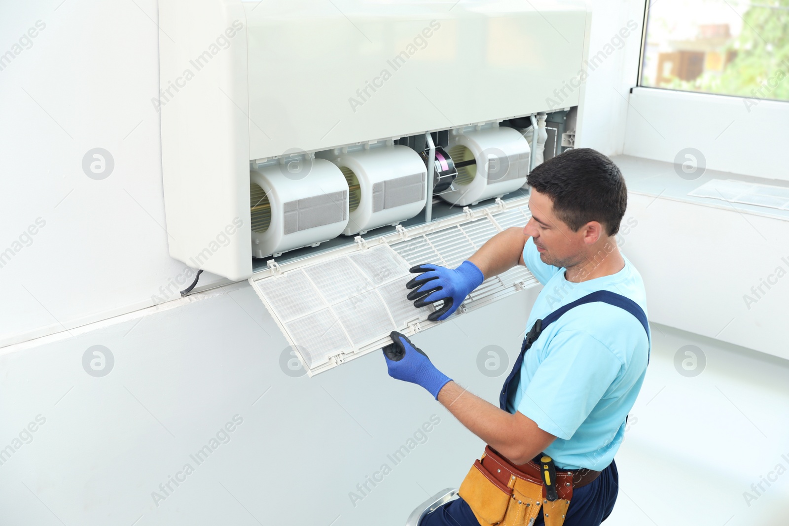 Photo of Male technician cleaning air conditioner indoors