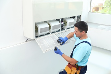 Photo of Male technician cleaning air conditioner indoors