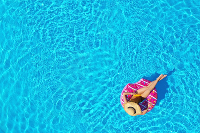 Young woman with inflatable ring in swimming pool, top view. Space for text