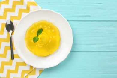 Photo of Plate of tasty fruit jelly served on blue wooden table, flat lay with space for text