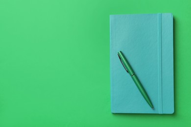 Photo of New stylish planner with hard cover and pen on green background, top view. Space for text