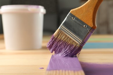 Photo of Applying violet paint onto wooden surface, closeup. Space for text