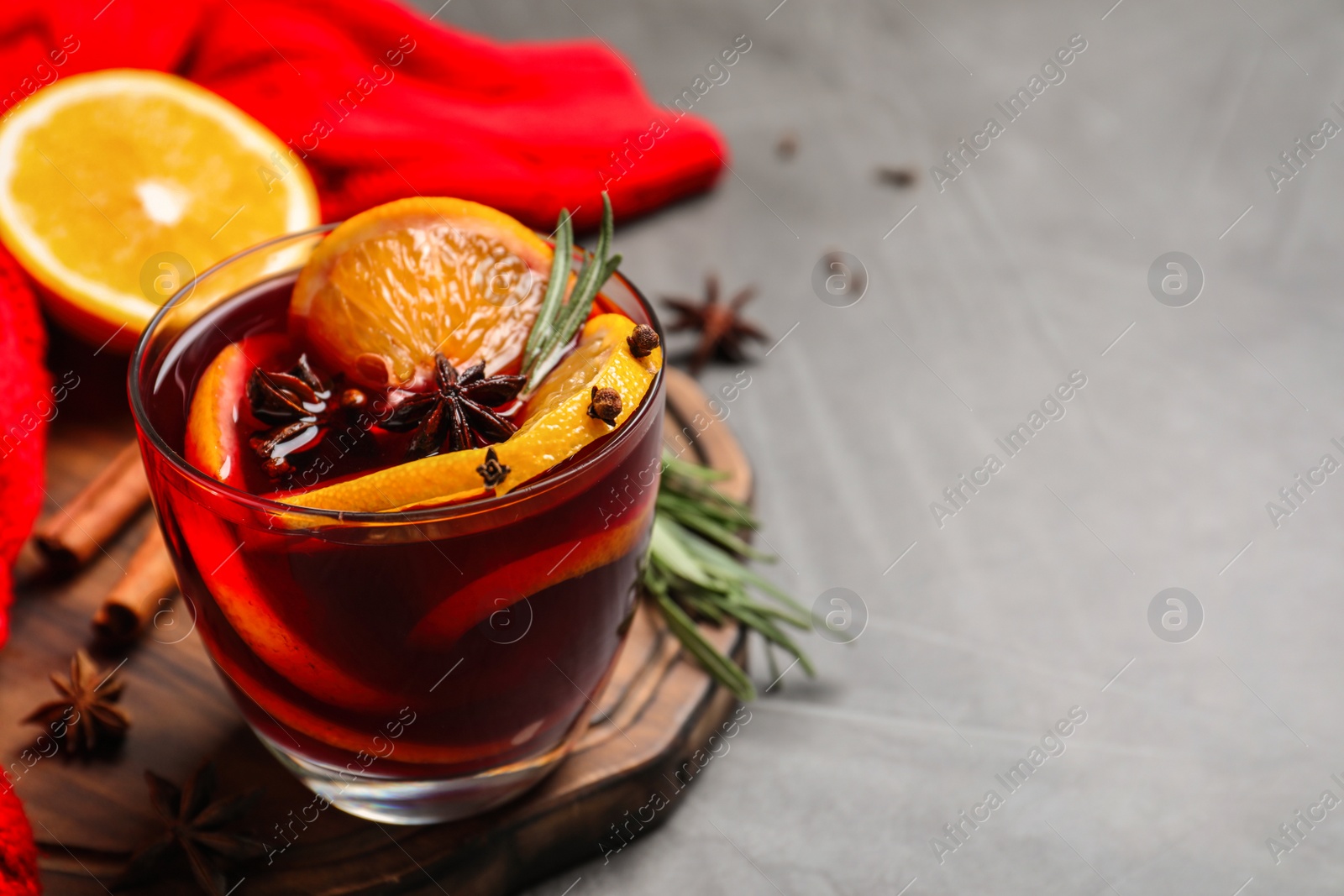 Photo of Glass with aromatic mulled wine on grey table. Space for text