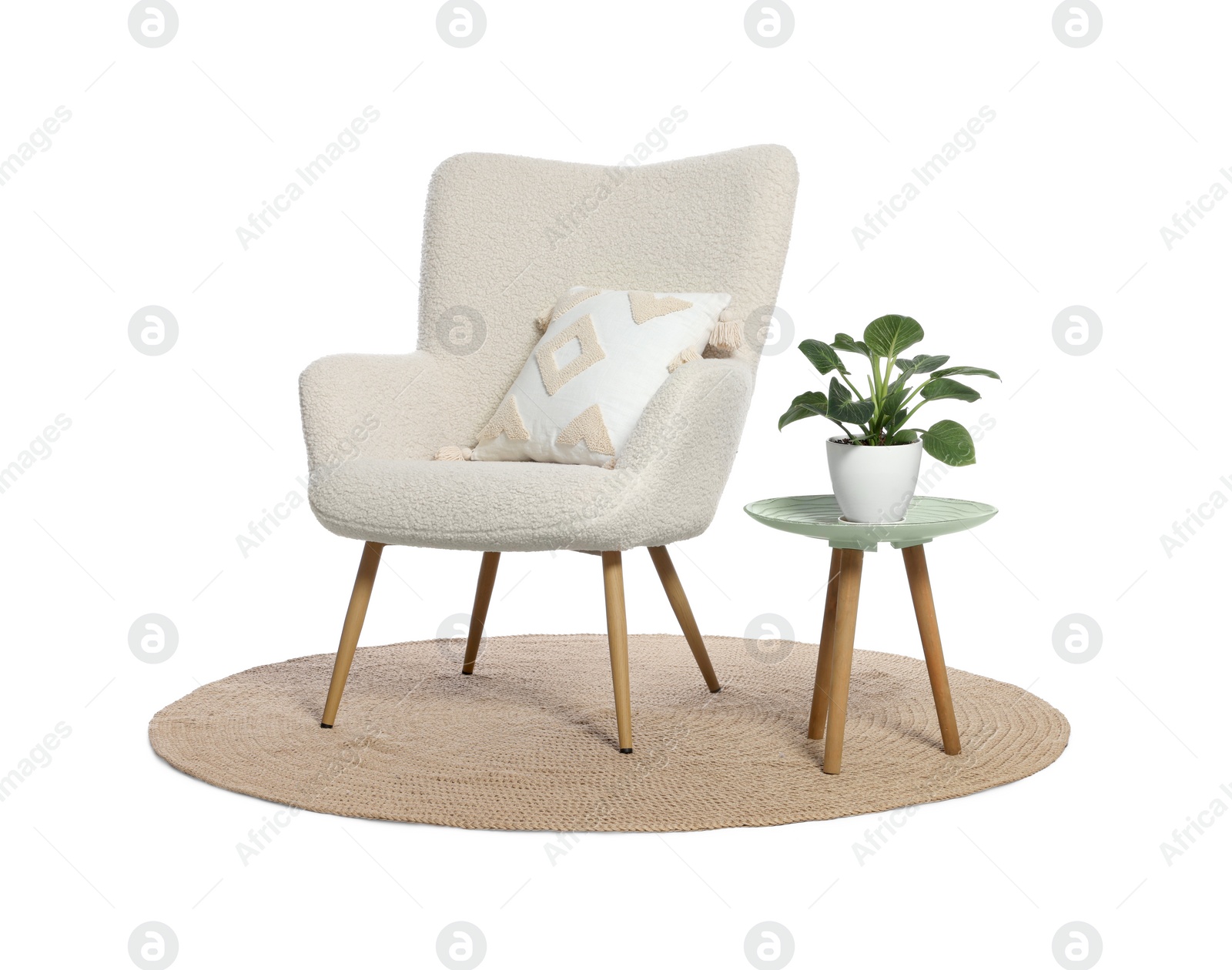 Photo of One stylish comfortable armchair with pillow, small table, houseplant and rug isolated on white