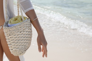 Woman with beach bag near sea, closeup
