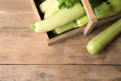 Photo of Crate with ripe zucchinis on wooden table, flat lay. Space for text