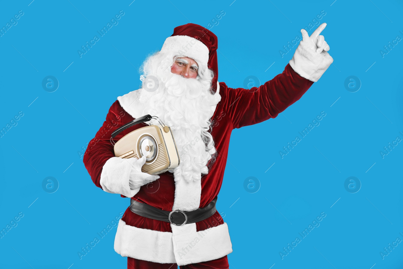 Photo of Santa Claus with vintage radio on blue background. Christmas music