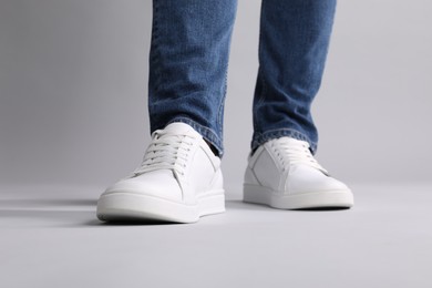 Photo of Man wearing stylish white sneakers on grey background, closeup